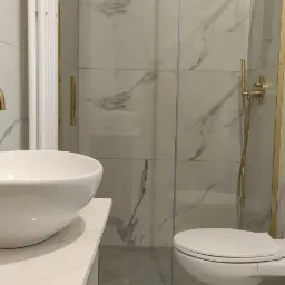 Nowoczesna łazienka z kabiną prysznicową ze złotymi elementami, umywalką nablatową i wzorzystą podłogą.