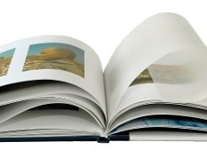 Otwarty album ze zdjęciami krajobrazów, widoczne grube, białe kartki i ciemnoniebieska oprawa.