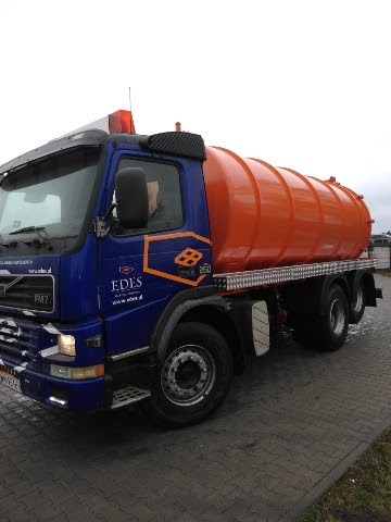 Ciężarówka asenizacyjna Volvo FM7 z pomarańczową cysterną, zaparkowana na brukowanym placu, z widocznym logo firmy EDES na niebieskiej kabinie.