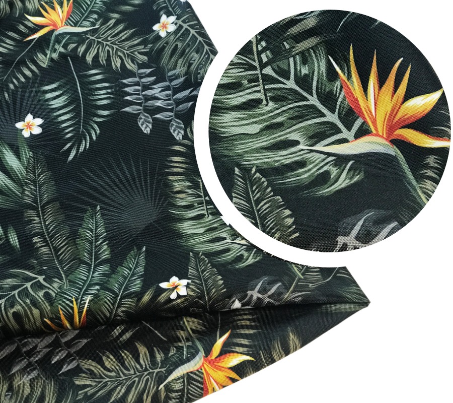 Ciemna tkanina z motywem tropikalnych liści i kwiatów rajskiego ptaka, powiększenie fragmentu wzoru w okręgu.