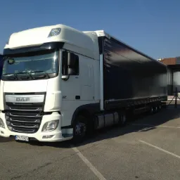 Biała ciężarówka DAF XF z czarną plandeką na parkingu w słoneczny dzień, widoczna tablica rejestracyjna ZS 759GU.