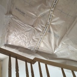 Lukasz Witek - Folia paroizolacyjna Isover Vario KB 1 zabezpiecza sufit podczas prac remontowych, widoczna drewniana balustrada schodów i fragment drabiny.