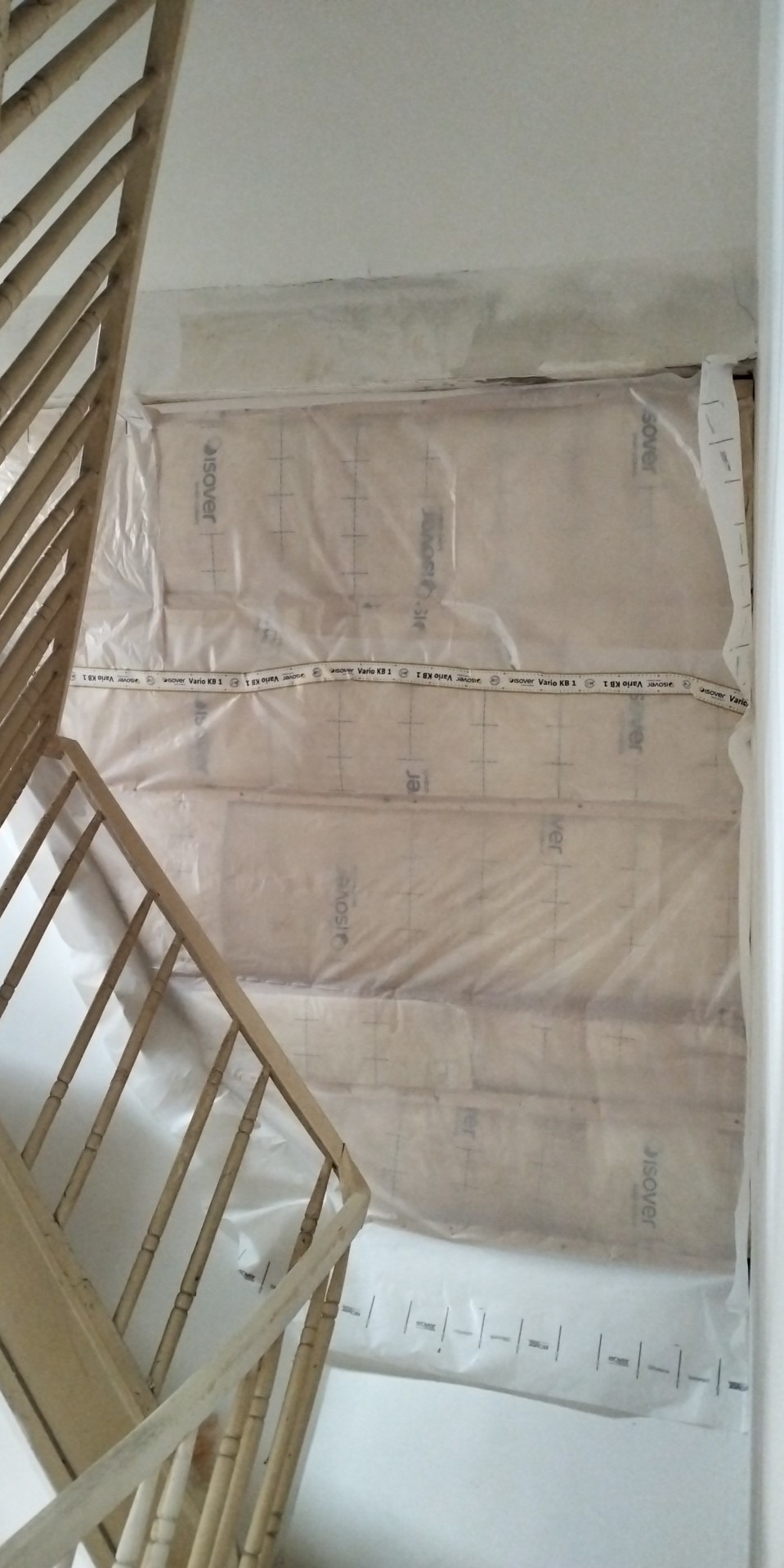 Schody zabezpieczone folią ochronną Isover Vario KB 1 podczas prac remontowych, widoczne ślady po starym malowaniu na ścianie.