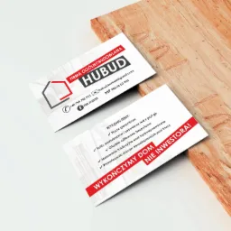 Dwie wizytówki firmy ogólnobudowlanej Hubud leżące na drewnianym blacie, prezentujące logo, dane kontaktowe oraz zakres usług.