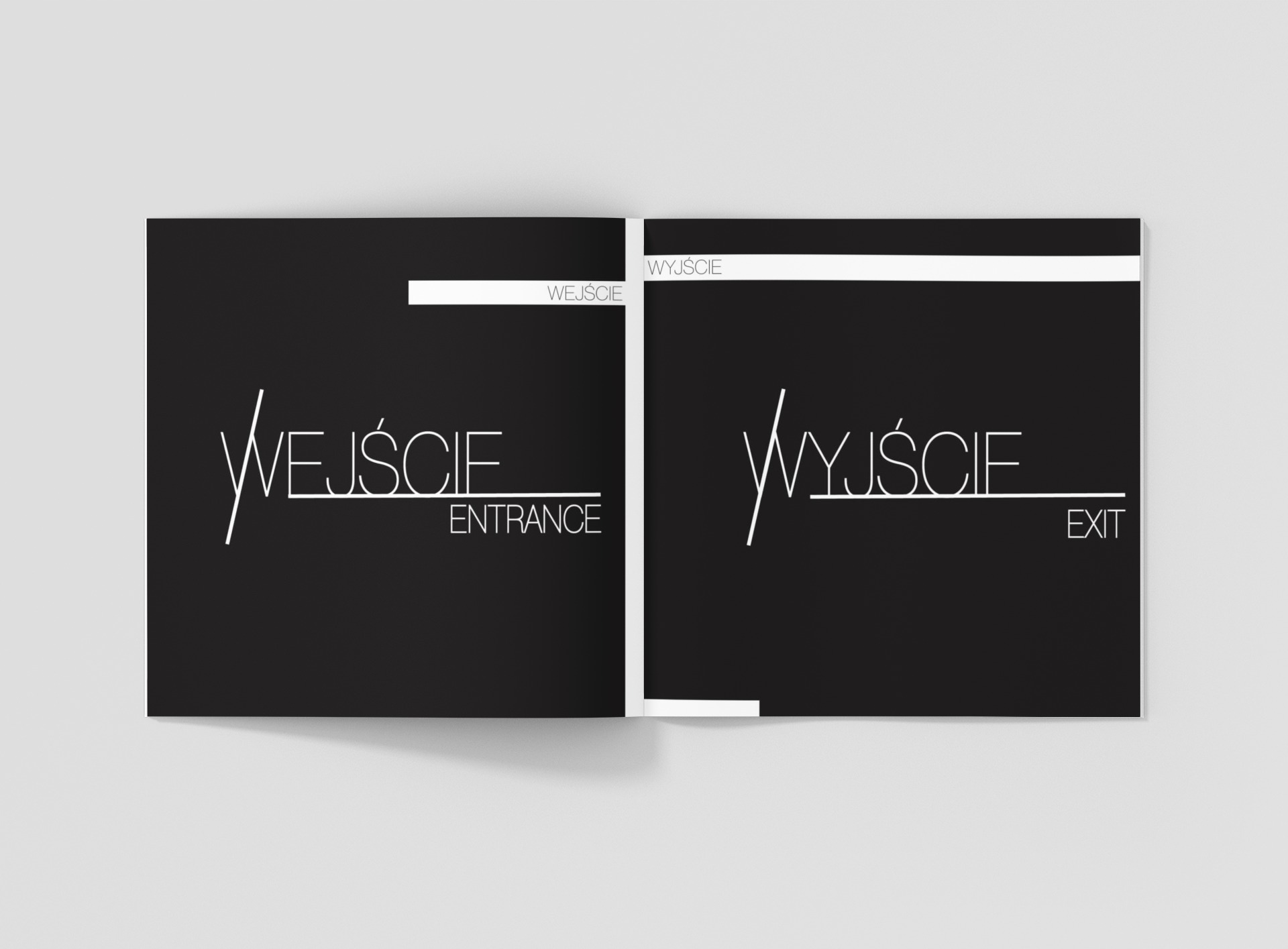 Otwarta książka z czarnymi stronami, na których widnieją białe napisy 'Wejście Entrance' i 'Wyjście Exit' w nowoczesnej typografii, prezentowana na jasnoszarym tle.