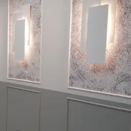 Dwa nowoczesne, podświetlane panele ścienne z geometrycznym wzorem na ozdobnej, szarej ścianie w stylu klasycznym.