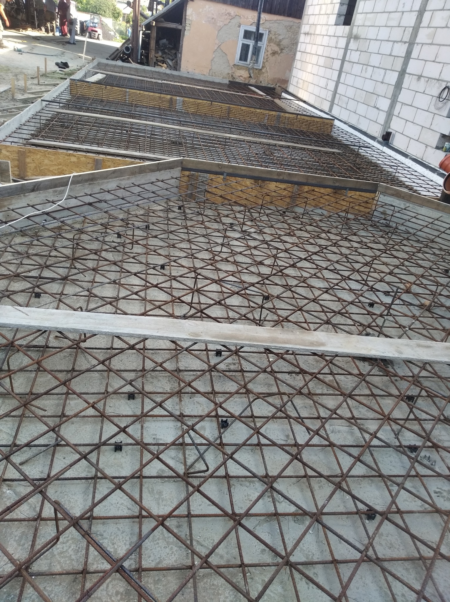 Zbrojenie stropu domu jednorodzinnego z widocznymi elementami szalunkowymi i betonem w tle, widok z góry.