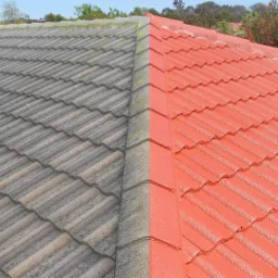 Częściowo odnowiony dach z dachówki ceramicznej, po lewej stronie widoczny stary, szary dach, po prawej pomalowany na czerwono-pomarańczowy kolor.