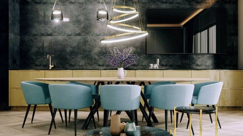 Nowoczesna jadalnia z owalnym stołem, turkusowymi krzesłami, wiszącą lampą pierścieniową i dekoracyjną ścianą w odcieniach szarości.