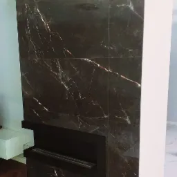 Ściana wykończona ciemnym, marmurkowym gresem z wbudowanym, nowoczesnym biokominkiem w czarnej obudowie.