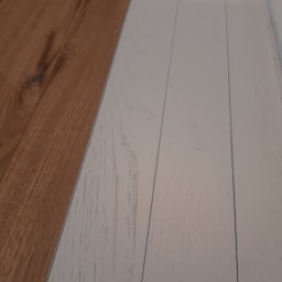 STOL-Design - Fragment blatu: połowa z surowego drewna, druga połowa pomalowana na biało z widoczną strukturą drewna.