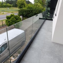 MS-PRO Marek Szczepanek - Nowoczesna balustrada szklana na balkonie z widokiem na ulicę i zaparkowany samochód dostawczy.