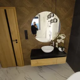 Nowoczesna łazienka z umywalką nablatową, lustrem w okrągłej ramie odbijającym wannę wolnostojącą i lampę wiszącą, drewnianą ścianą z geometrycznym wzorem i drewnianymi drzwiami z czarnymi akcentami.