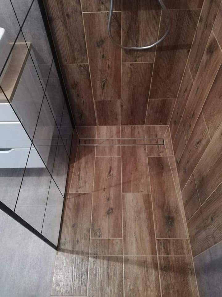 Wykończona kabina prysznicowa z odpływem liniowym i płytkami imitującymi drewno na ścianach i podłodze, widok z góry.