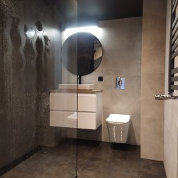 Glazurem - łazienki, wykończenia wnętrz - Nowoczesna łazienka z kabiną prysznicową typu walk-in, heksagonalnymi płytkami na ścianie, okrągłym lustrem z podświetleniem, wiszącą szafką z umywalką oraz wiszącą toaletą.