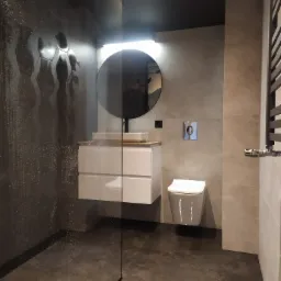 Nowoczesna łazienka z kabiną prysznicową typu walk-in, heksagonalnymi płytkami na ścianie, okrągłym lustrem z podświetleniem, wiszącą szafką z umywalką oraz wiszącą toaletą.