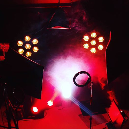 Scena oświetlona intensywnym czerwonym światłem z efektem dymu, widoczne reflektory punktowe i panele LED, tworzące dramatyczny nastrój wizualny.