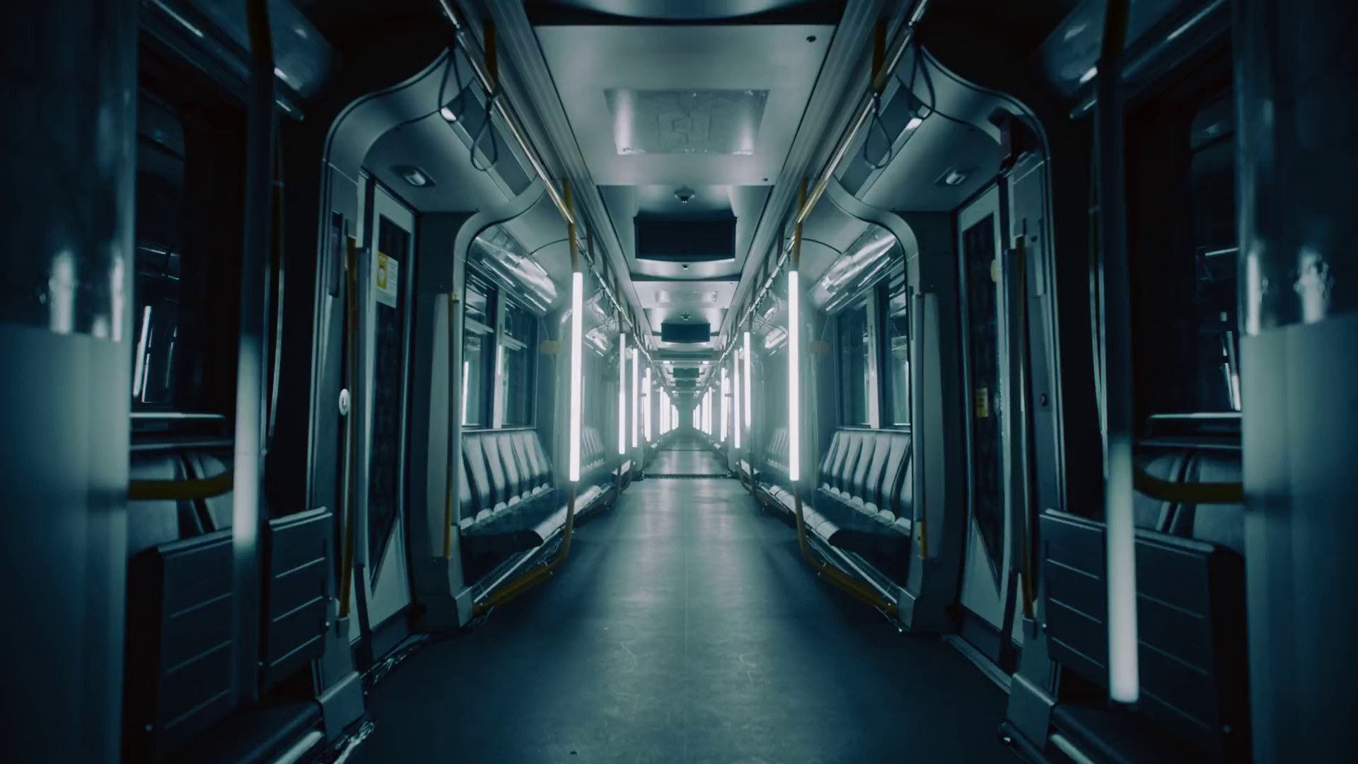 Wnętrze nowoczesnego wagonu metra z podłużnymi, pionowymi lampami LED, szarymi siedzeniami i metalowymi elementami wykończenia, widziane w perspektywie zbieżnej.