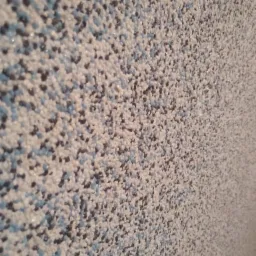 Dekoracyjna ściana pokryta tynkiem mozaikowym w odcieniach bieli, błękitu i szarości, z delikatnym połyskiem