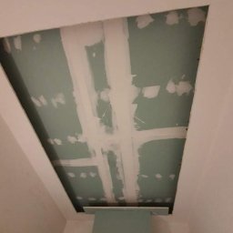 SzWykończenia - Montaż płyty karton gips na suficie w Szczecinie, widoczne łączenia wzmocnione taśmą i częściowo zaszpachlowane, sufit przygotowywany do dalszych prac wykończeniowych.