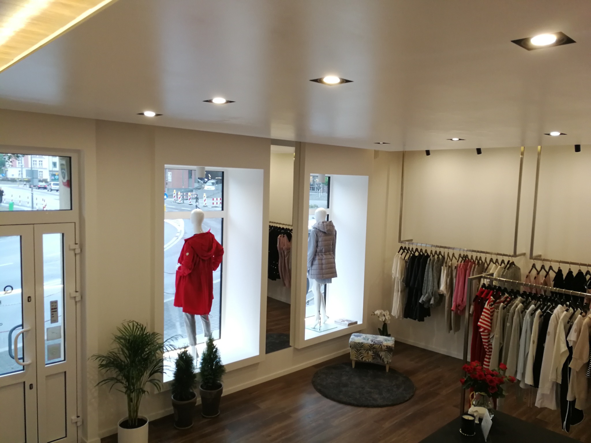 Jasne wnętrze butiku odzieżowego z manekinami w oknach i wieszakami z ubraniami, widok z góry