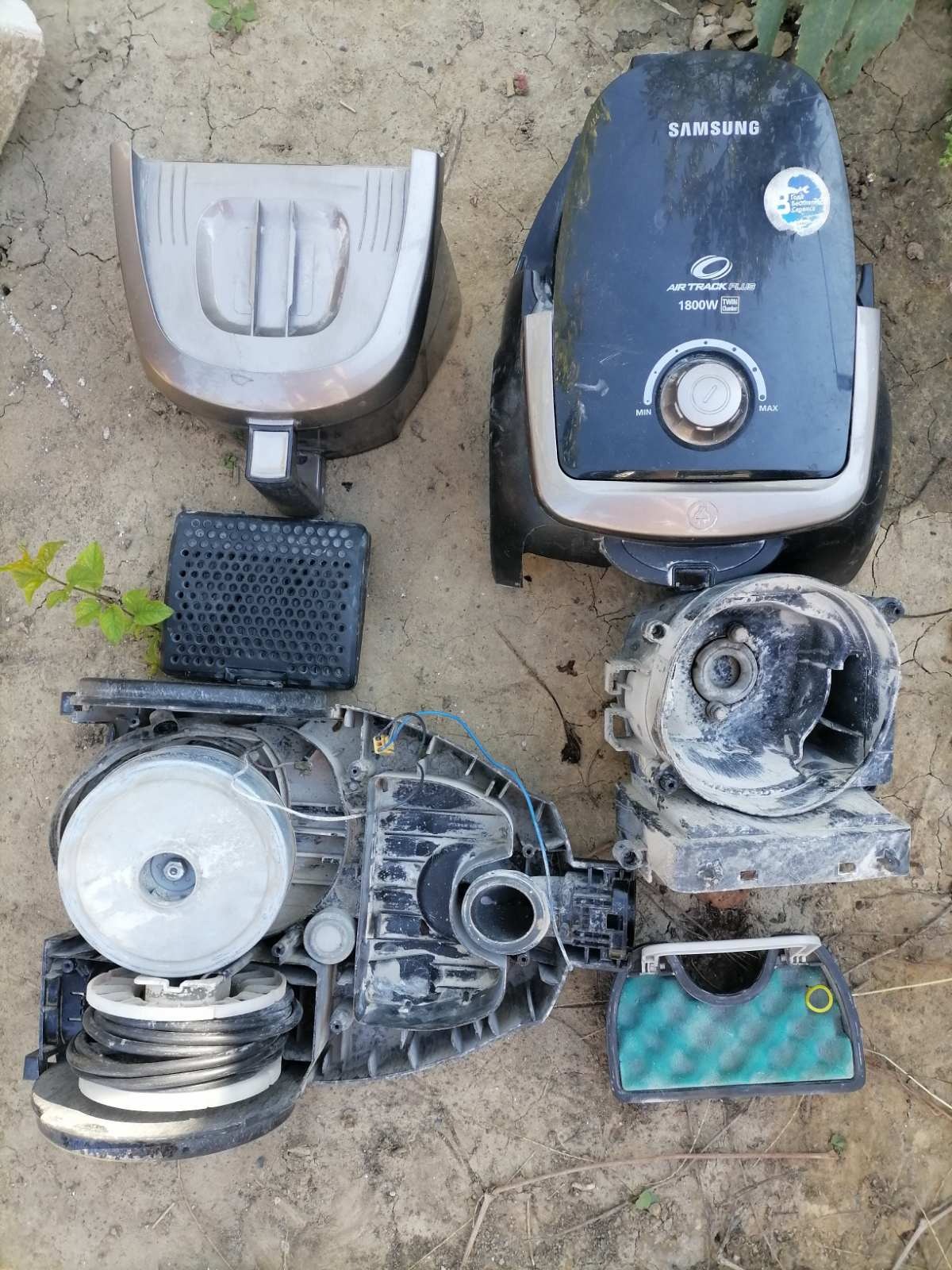 Rozłożony na części, brudny odkurzacz Samsung Air Track Plus 1800W na ziemi, widoczne elementy obudowy, filtr, silnik i przewody.