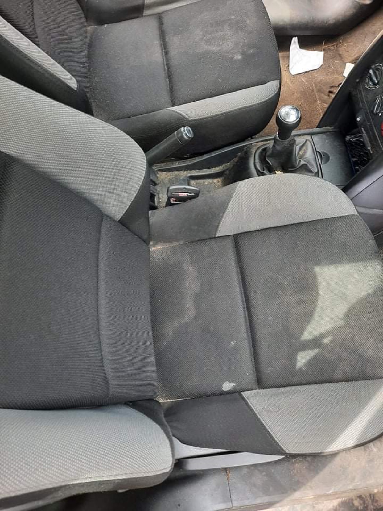 Brudne, szaro-czarne fotele samochodowe przed czyszczeniem w Poznaniu, widoczne plamy i zabrudzenia na tapicerce.