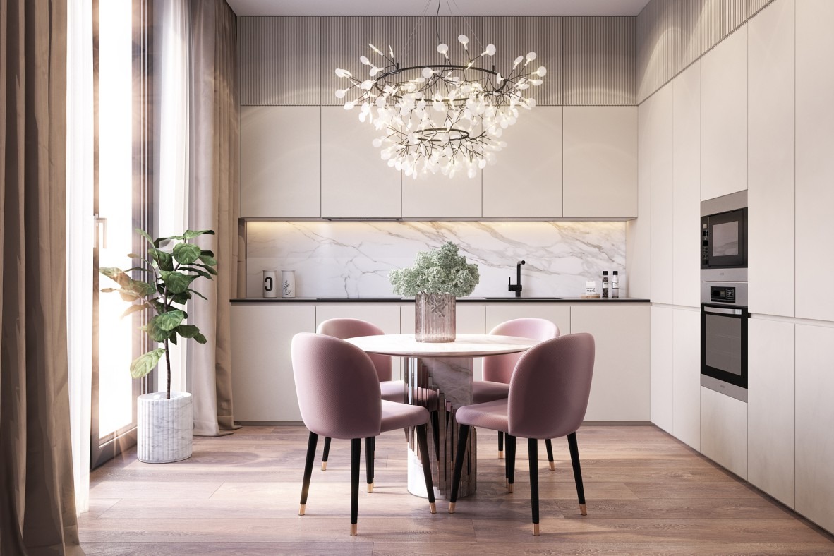 Jasna kuchnia z okrągłym stołem i różowymi krzesłami, nad stołem nowoczesny żyrandol, na blacie marmurowy wzór, obok okna roślina w doniczce.