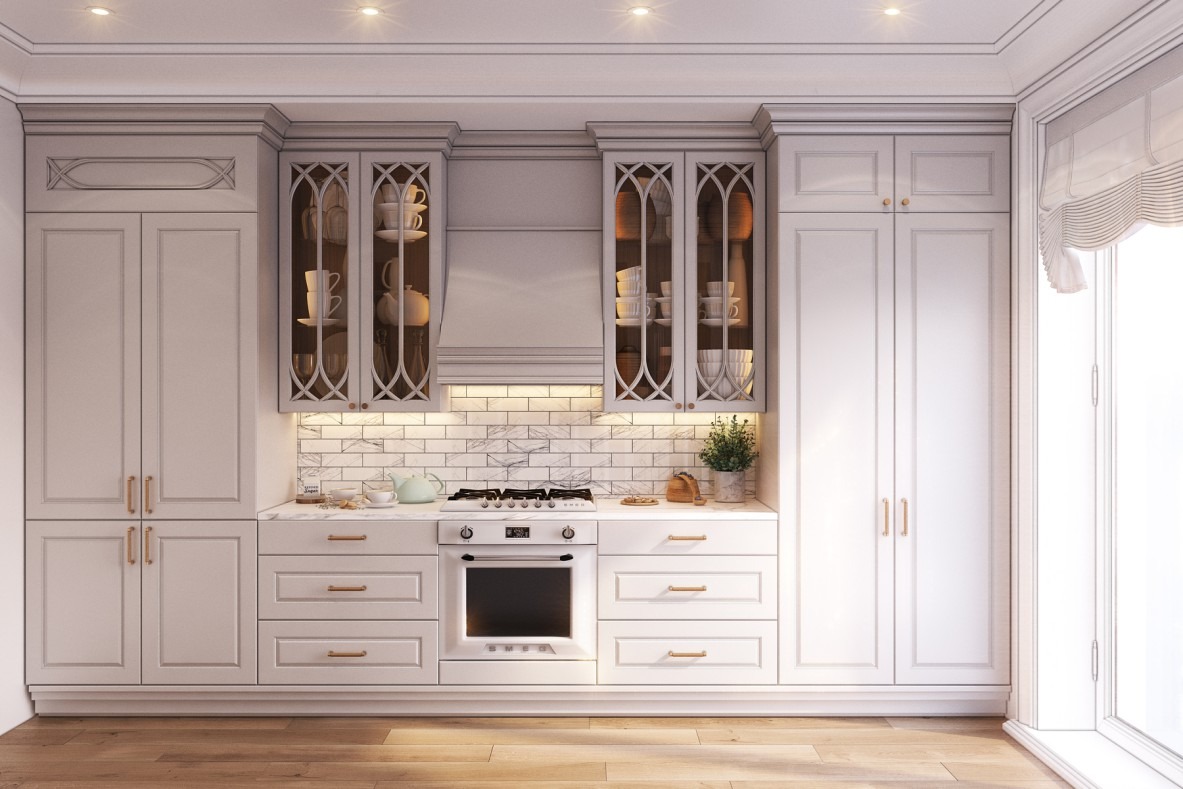 Elegancka, jasna kuchnia w Suchym Dworze z białymi szafkami, marmurowym blatem i drewnianą podłogą. Szafki górne przeszklone, eksponujące porcelanę. Na blacie czajnik i roślina w doniczce.