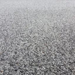 Szara, żywiczna posadzka z kamyczków na balkonie, widok z dołu, z czarną balustradą w tle.