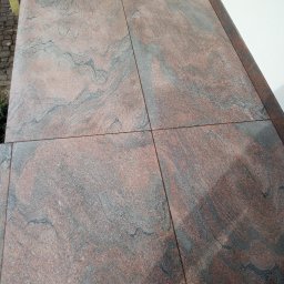 Remont Dla Ciebie - Ułożona, brązowo-szara, wzorzysta podłoga z płytek ceramicznych na zewnątrz budynku, widok z góry.