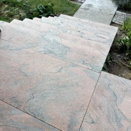 Remont Dla Ciebie - Zewnętrzne schody wyłożone płytami z różowo-szarego granitu z wyraźnym wzorem, prowadzące do betonowego chodnika w ogrodzie.