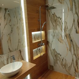 Remont Dla Ciebie - Nowoczesna łazienka z drewnianymi akcentami: umywalka nablatowa, kabina prysznicowa typu walk-in z marmurowymi płytkami i podświetlane wnęki. Designerskie wykończenie.