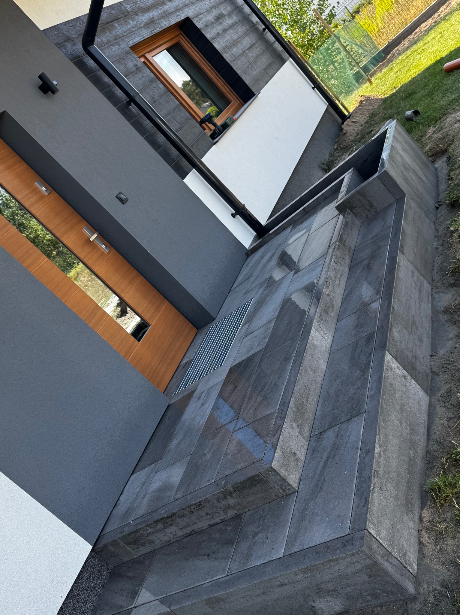 Nowoczesne wykończenie elewacji z użyciem ciemnych płyt kamiennych, widoczne detale architektoniczne w Brzozie. Elegancki design i precyzja wykonania.