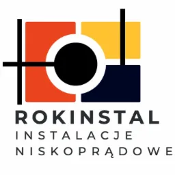Logo firmy ROKINSTAL z napisem INSTALACJE NISKOPRĄDOWE, grafika w postaci kolorowych kwadratów: pomarańczowy, żółty, granatowy, przeciętych liniami tworzącymi okrąg z czarnym wypełnieniem.