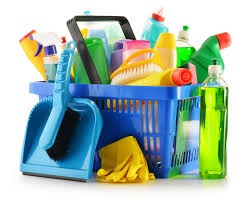 Niebieski koszyk wypełniony różnorodnymi środkami czystości, szczotkami i gumowymi rękawicami na białym tle.