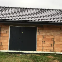 Nowy dach z ciemnej dachówki ceramicznej na budynku gospodarczym w Choroszczy, z widoczną rynną i surowymi ścianami z pustaków ceramicznych.