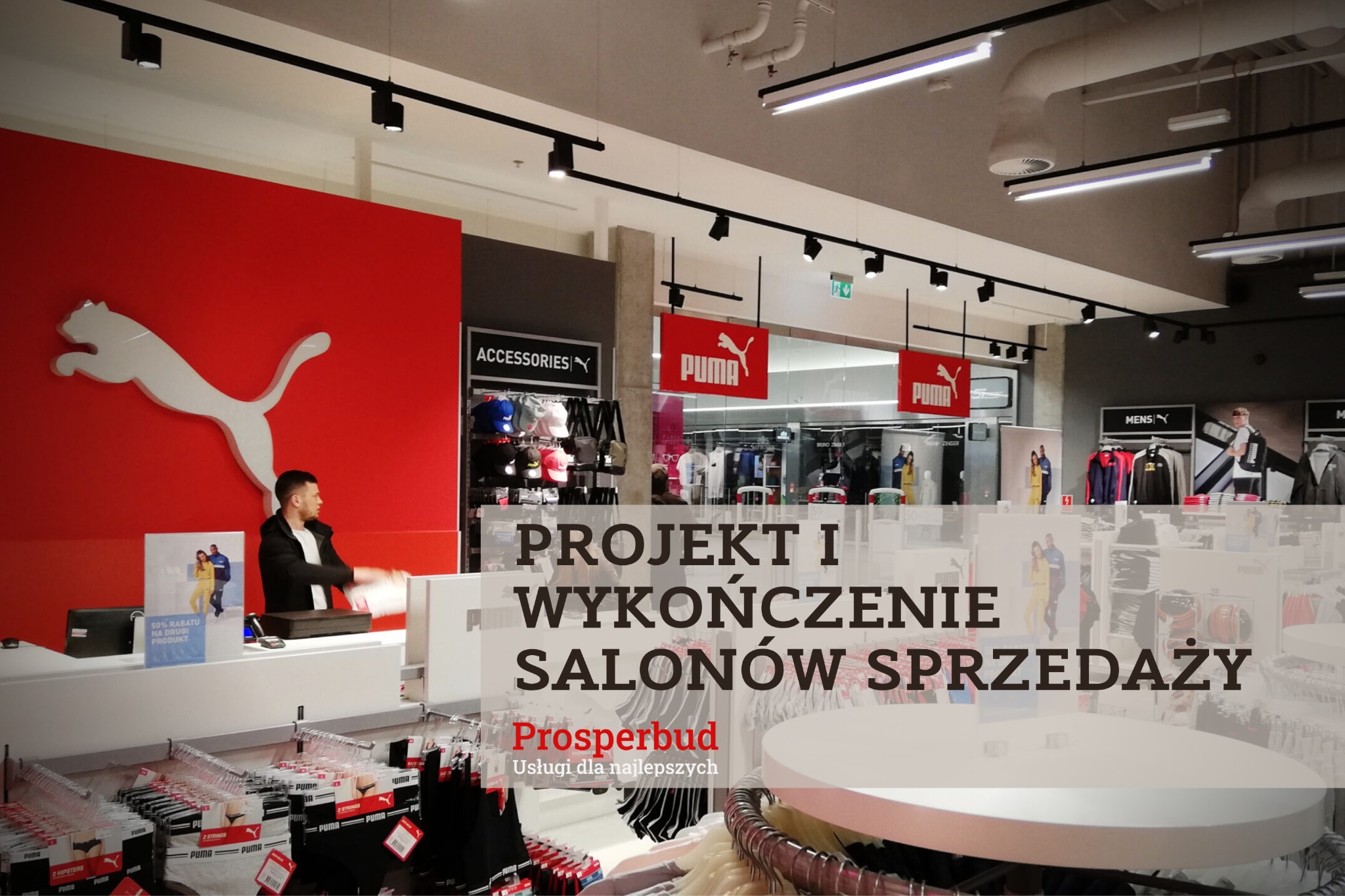 Wnętrze sklepu sportowego marki Puma, z widoczną strefą kasową, regałami z odzieżą i akcesoriami, oraz oświetleniem punktowym na szynach.