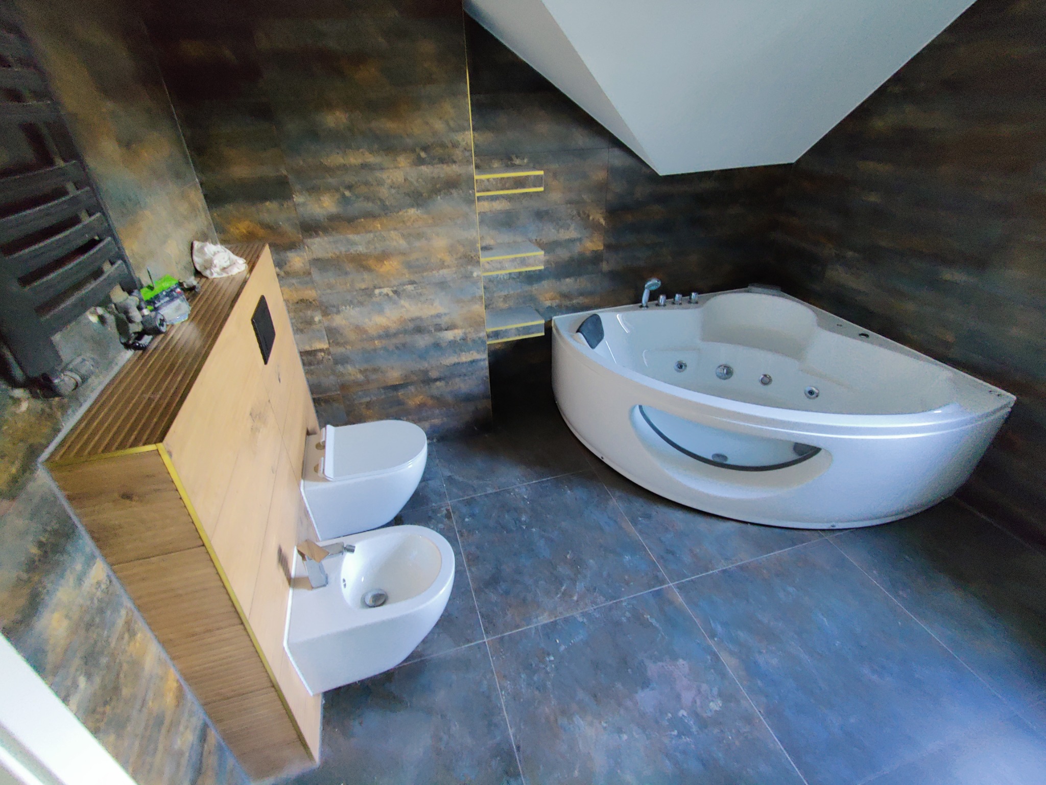 Wykończona łazienka w Głogowie z narożną wanną z hydromasażem, umywalką z bidetem i płytkami imitującymi rdzę na ścianach.