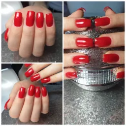 Czerwone, błyszczące paznokcie o kwadratowym kształcie, prezentowane na tle srebrnej mozaiki i dyskotekowej kuli, ukazujące precyzję wykonania.