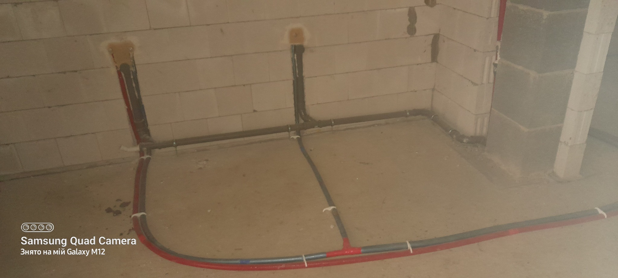 Instalacja rur wodnych i grzewczych w surowym stanie, widoczne rury prowadzone po ścianach z betonu komórkowego i podłodze, połączone złączkami, przygotowane do dalszych prac wykończeniowych.