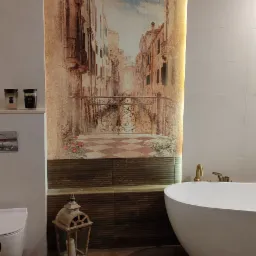 Nowoczesna łazienka z wolnostojącą wanną, drewnopodobną podłogą i fototapetą z motywem weneckim, oświetloną listwą LED.