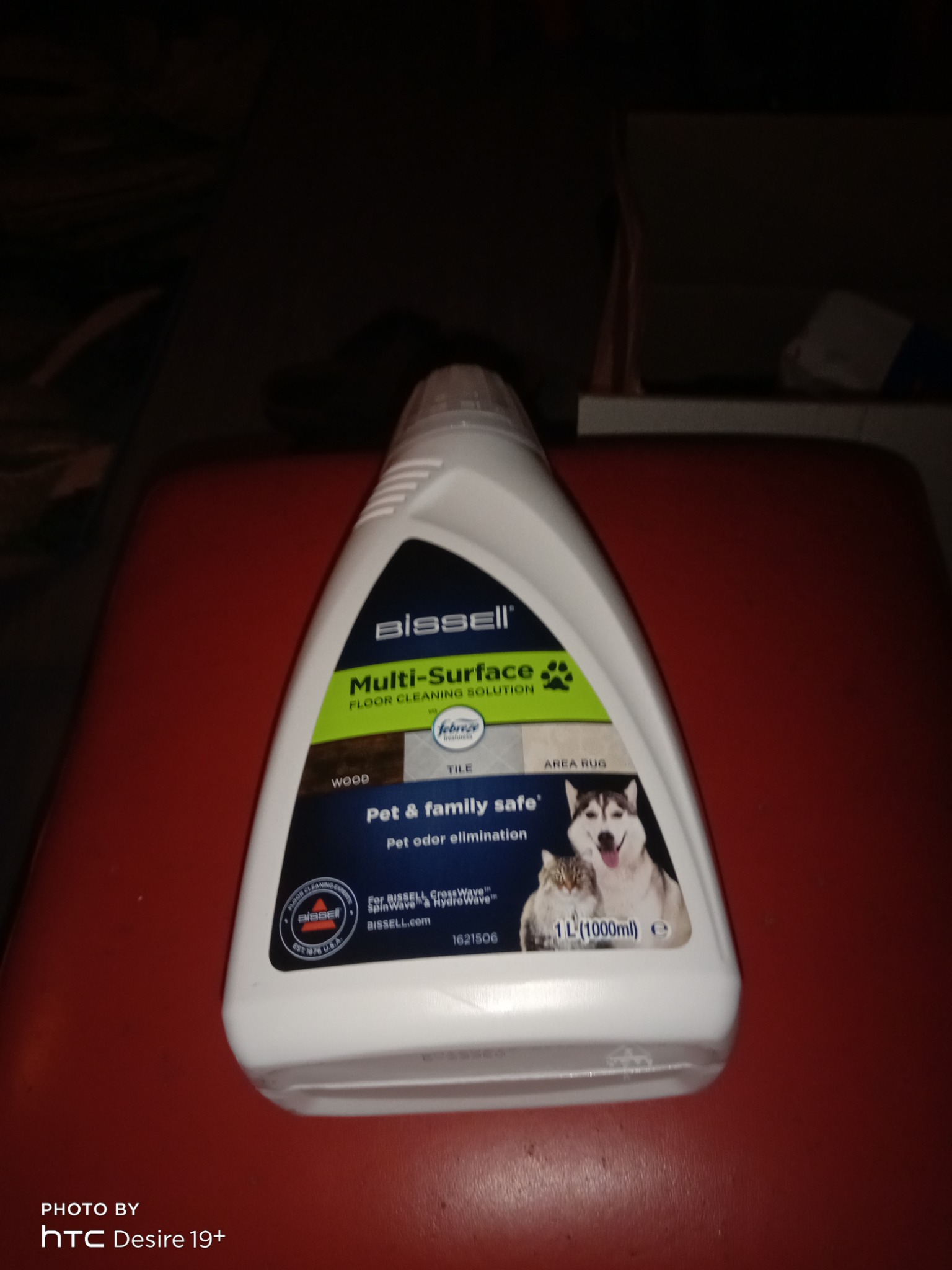 Biała butelka środka czyszczącego Bissell Multi-Surface Floor Cleaning Solution, przeznaczonego do czyszczenia podłóg drewnianych, płytek i dywanów, z dodatkiem Febreze i formułą bezpieczną...