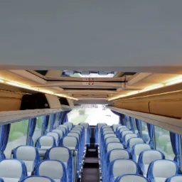 Wnętrze autobusu z rzędami niebiesko-białych foteli, schowkami nad głowami i zasłonami przy oknach, widok z przodu w kierunku wyjścia.