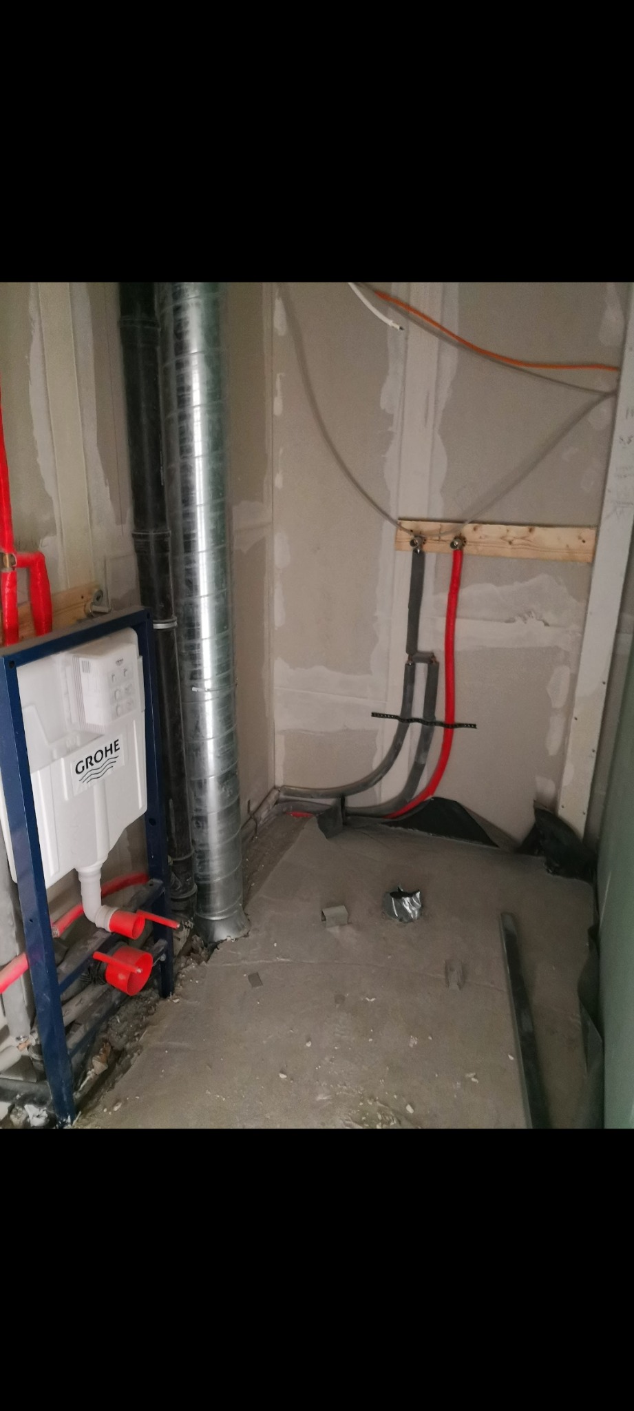 Montaż podtynkowego stelaża WC marki Grohe z widocznymi rurami doprowadzającymi wodę, fragmentem wentylacji i surowymi ścianami w trakcie remontu łazienki.