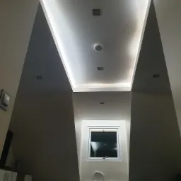 Skośne poddasze z oknem dachowym i oświetleniem LED wzdłuż krawędzi sufitu, widok z dołu.