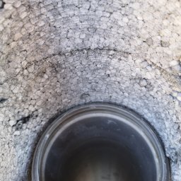 GOL MAR - Ocieplenie poddasza z widoczną rurą wentylacyjną, styropian z szarymi zabrudzeniami, widoczny fragment dłoni.