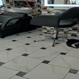 Global Labs sp. z o.o. - Nowoczesne wnętrze salonu fryzjerskiego z czarnym fotelem, umywalką i wzorzystą podłogą z płytek. Ściana wykończona dekoracyjną mozaiką.