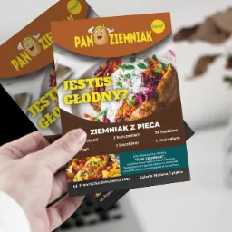 Dwa ulotki reklamowe restauracji 'Pan Ziemniak' prezentowane w dłoni, z grafiką pieczonego ziemniaka z dodatkami i informacją o lokalizacji w Galerii Morena.