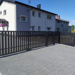 PPHU ROB-MAR Robert Marek - Nowoczesne, grafitowe ogrodzenie posesji z furtką, na tle dwukondygnacyjnego domu z numerem 42, w słoneczny dzień. Kostka brukowa na podjeździe.